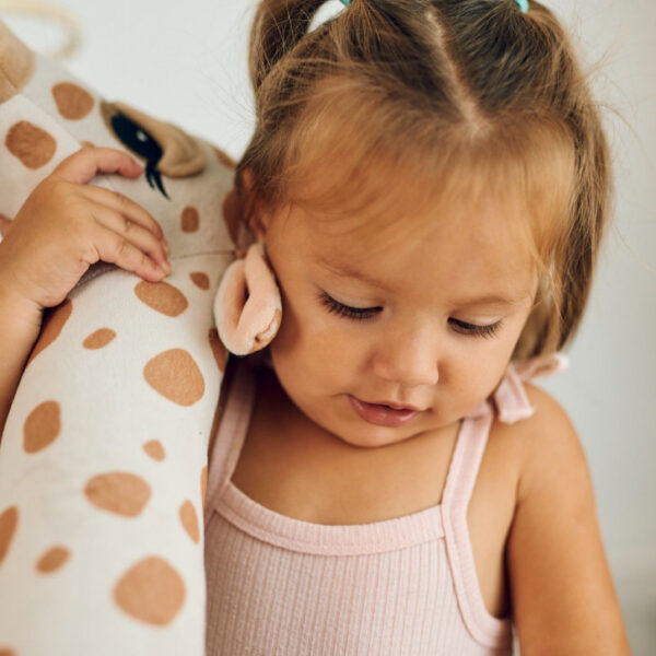 Малко момиче държи плюшен жираф.