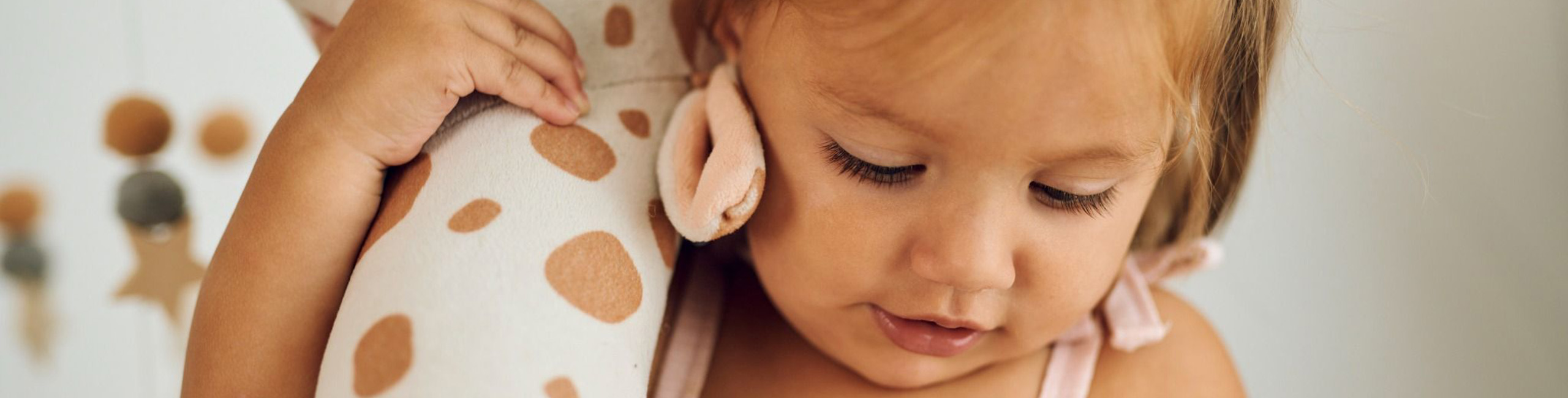 Малко момиче държи плюшен жираф.