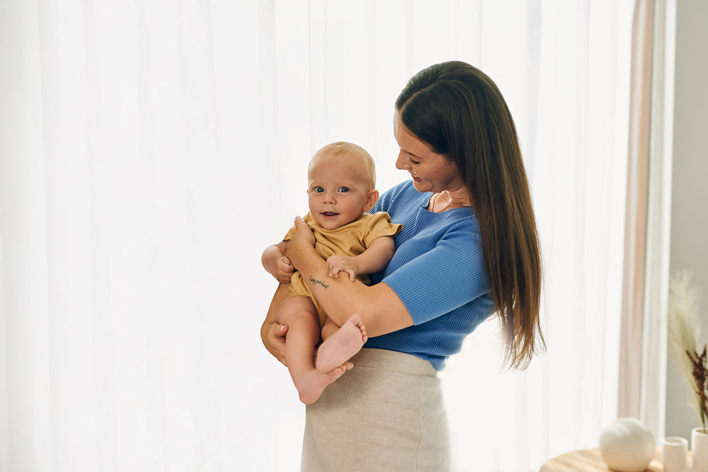 Майка държи бебето си в ръцете си и го гледа с любов.
