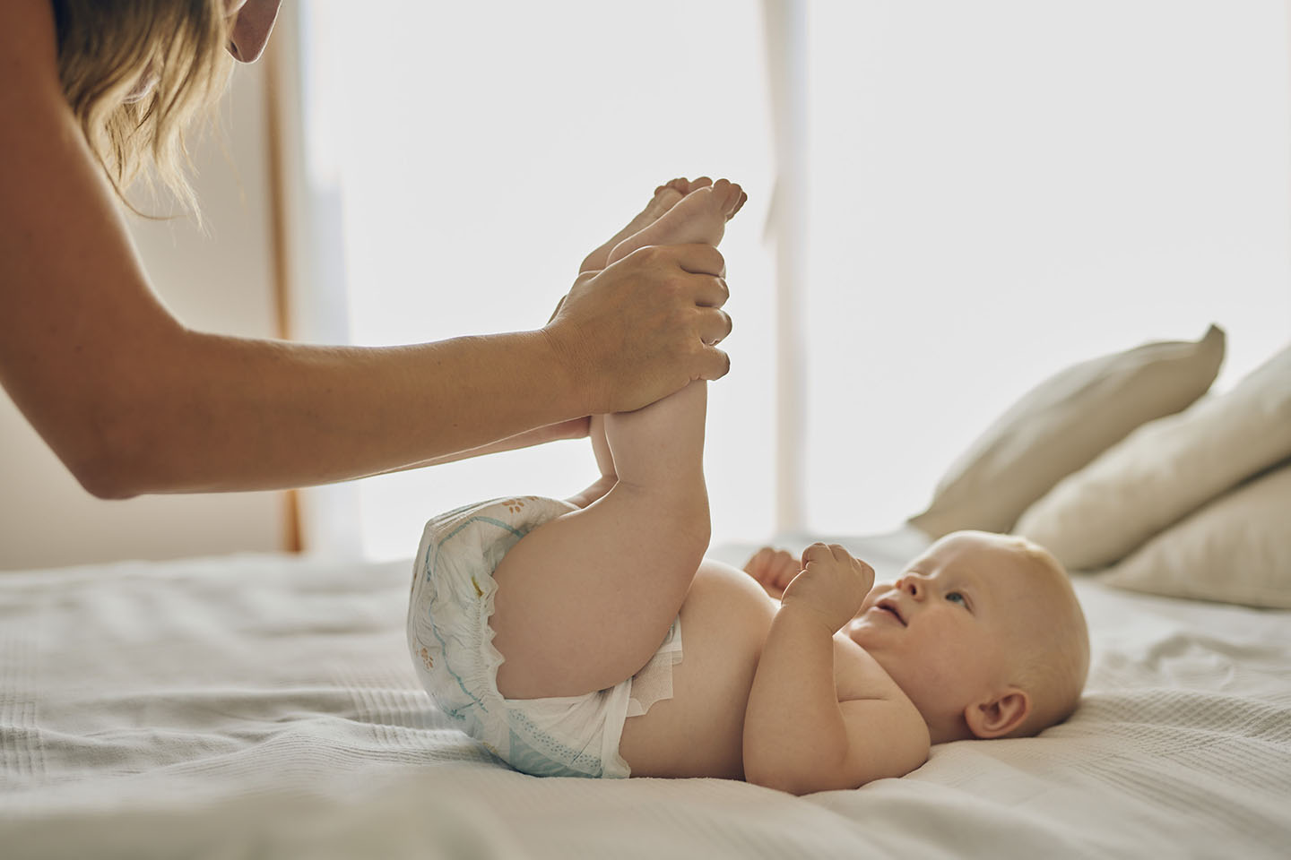 бебе на масата с крака във въздуха и памперс. преобличане