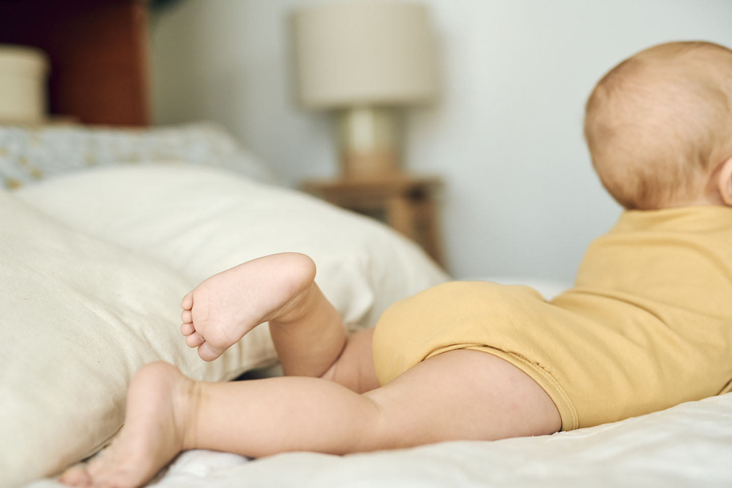 Бебето лежи на леглото.