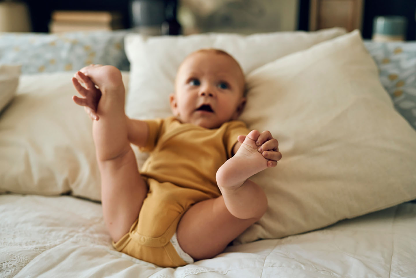Бебе лежи на легло с повдигнати крака