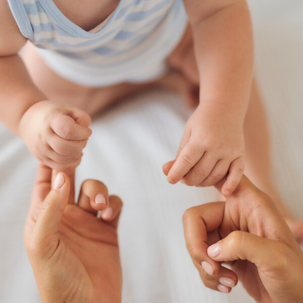 Бебе, държащо пръстите на майка си