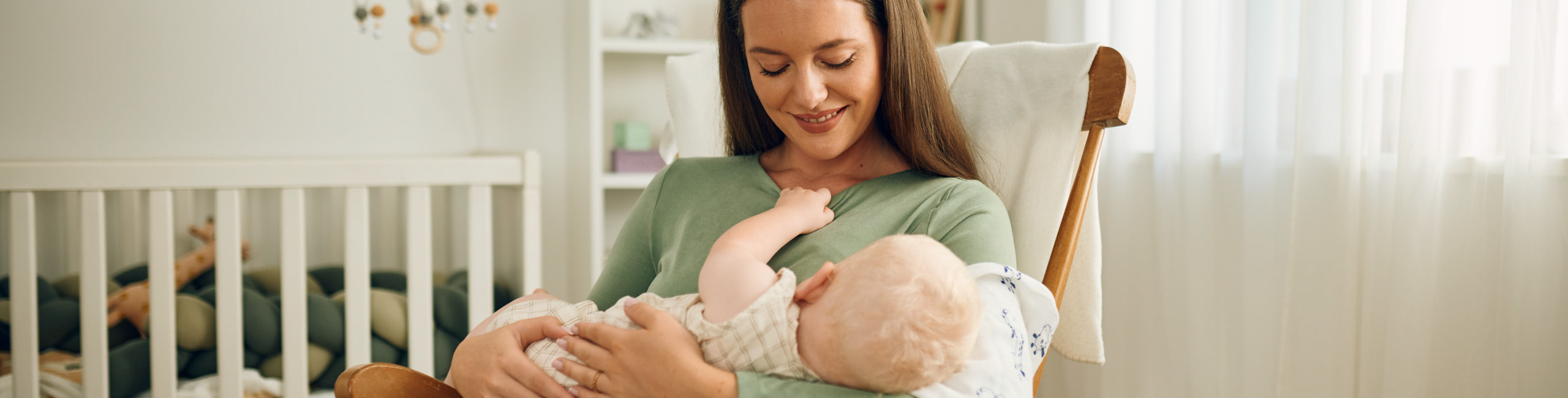 Майка на люлка с бебе на ръце.