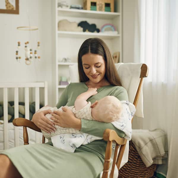 Майка на люлка с бебе на ръце.