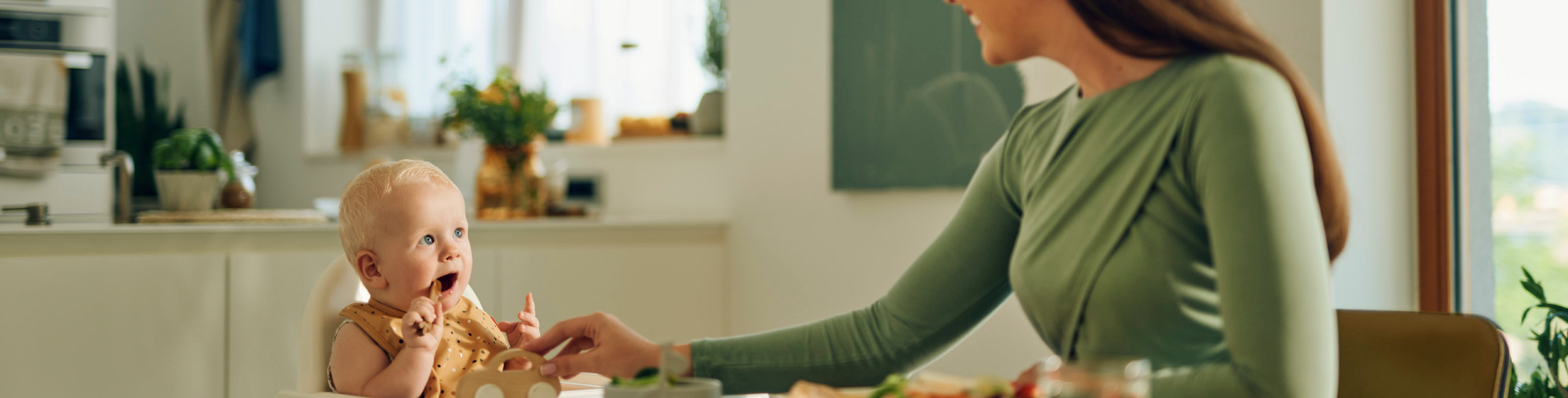 Бебе и майка на масата по време на хранене.