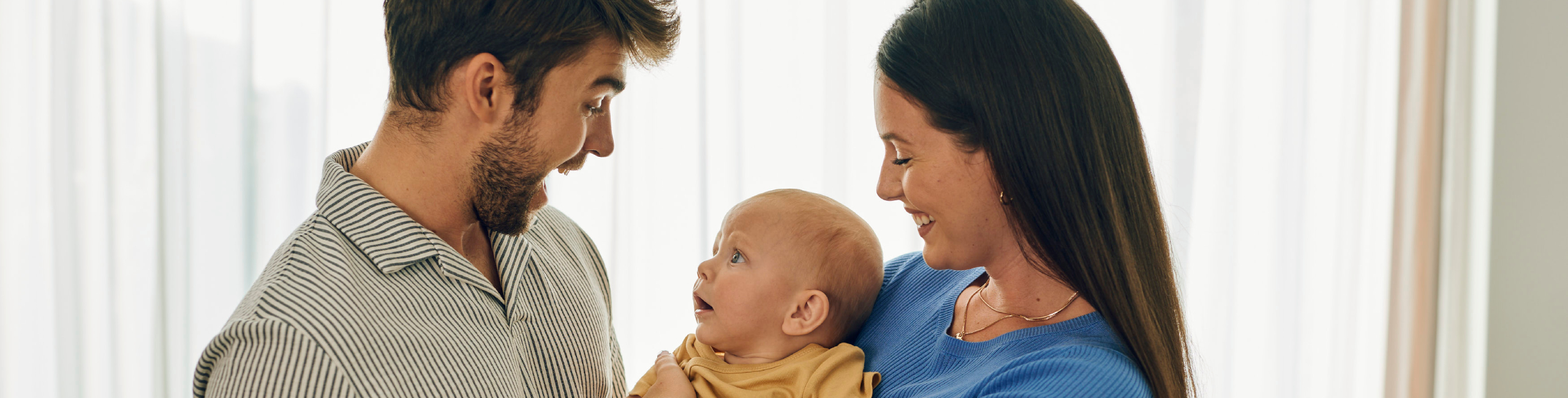 Родители с бебе на ръце – щастлив момент у дома.
