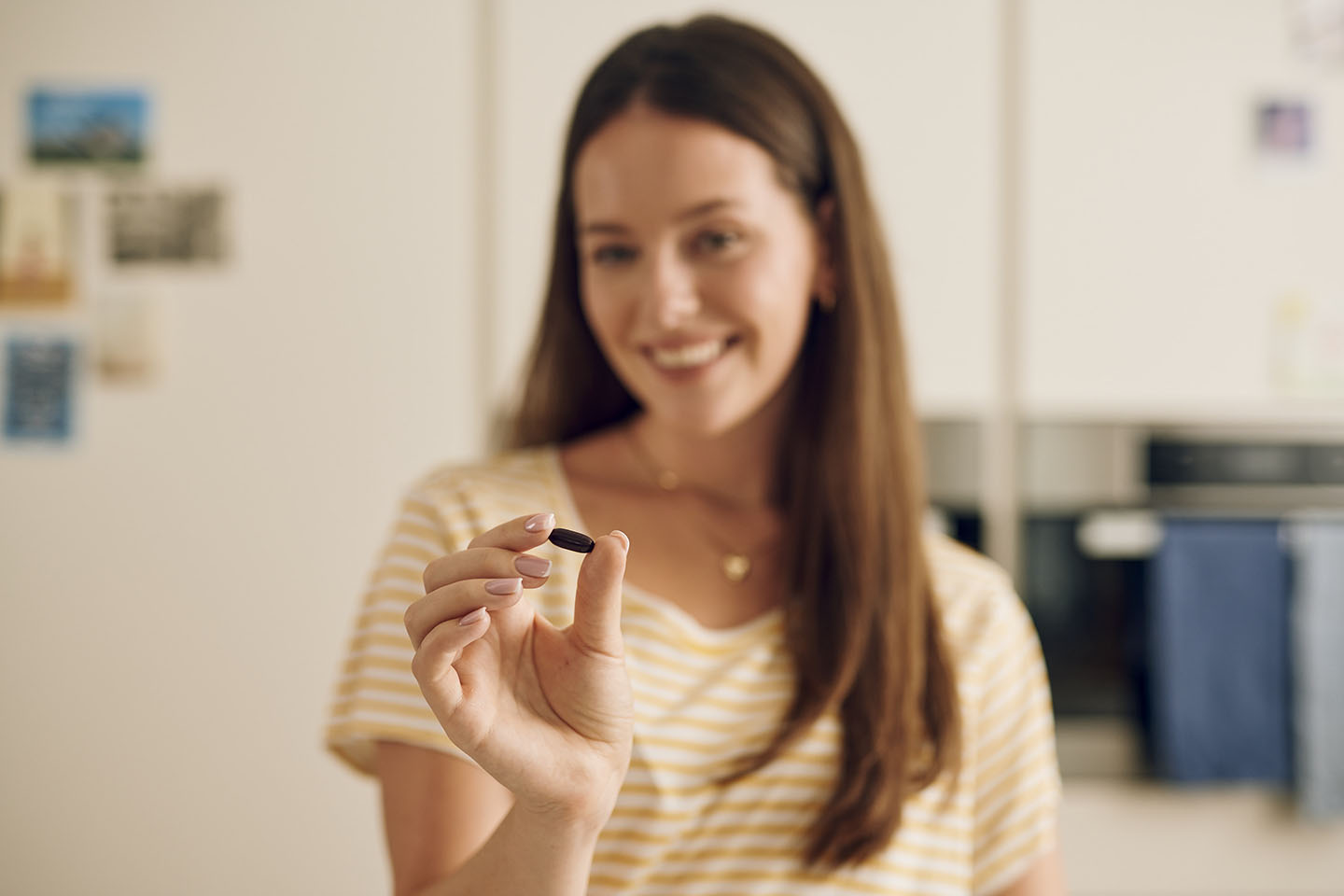 Жена държи пренатална капсула Novalac и се готви да я преглътне.