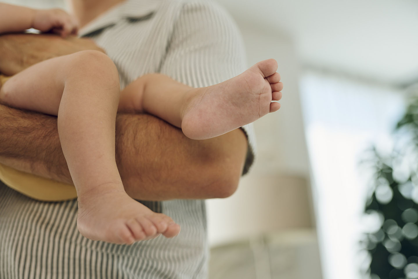 Кадър на детски крак в ръцете на родител