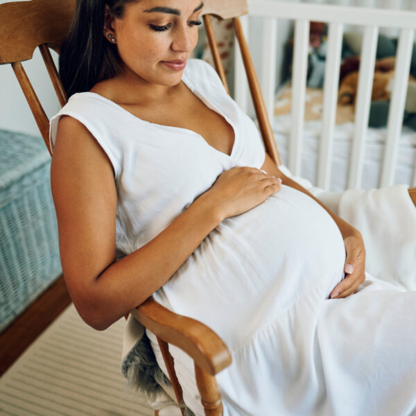 Бременна жена седи отпусната в люлка