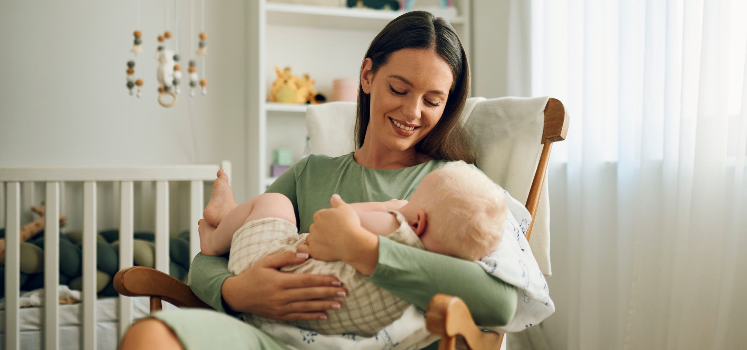 Майка държи бебето си на ръце, подготвяйки се за кърмене, след раждането.
