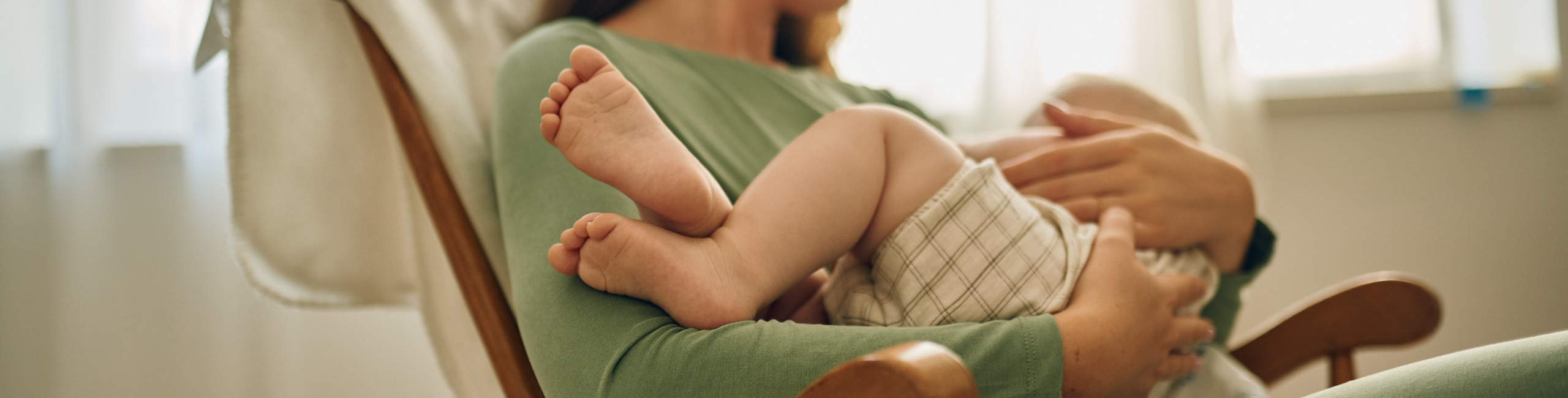 Майката държи бебето в ръцете си.