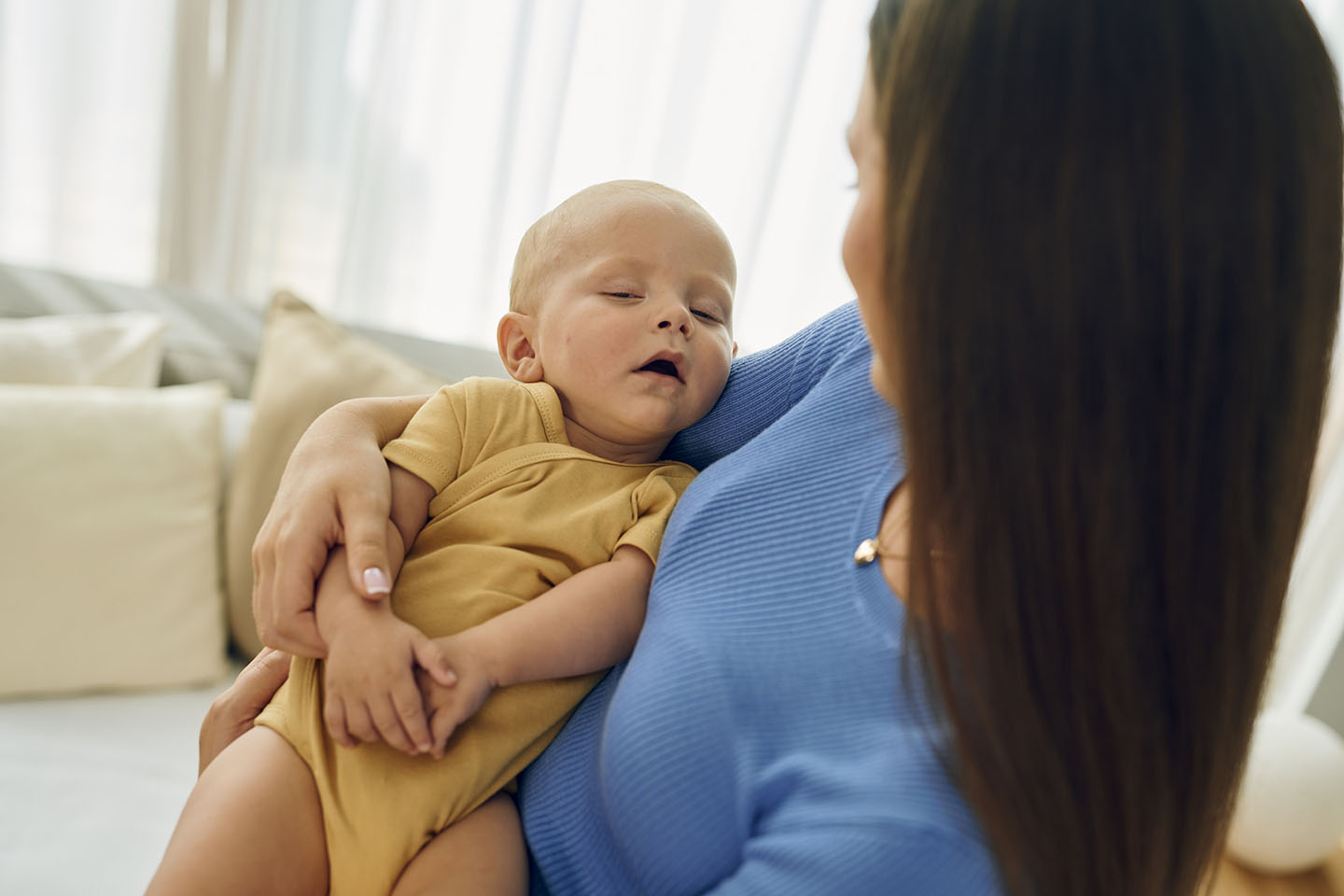 Майка държи спящо дете в ръцете си.
