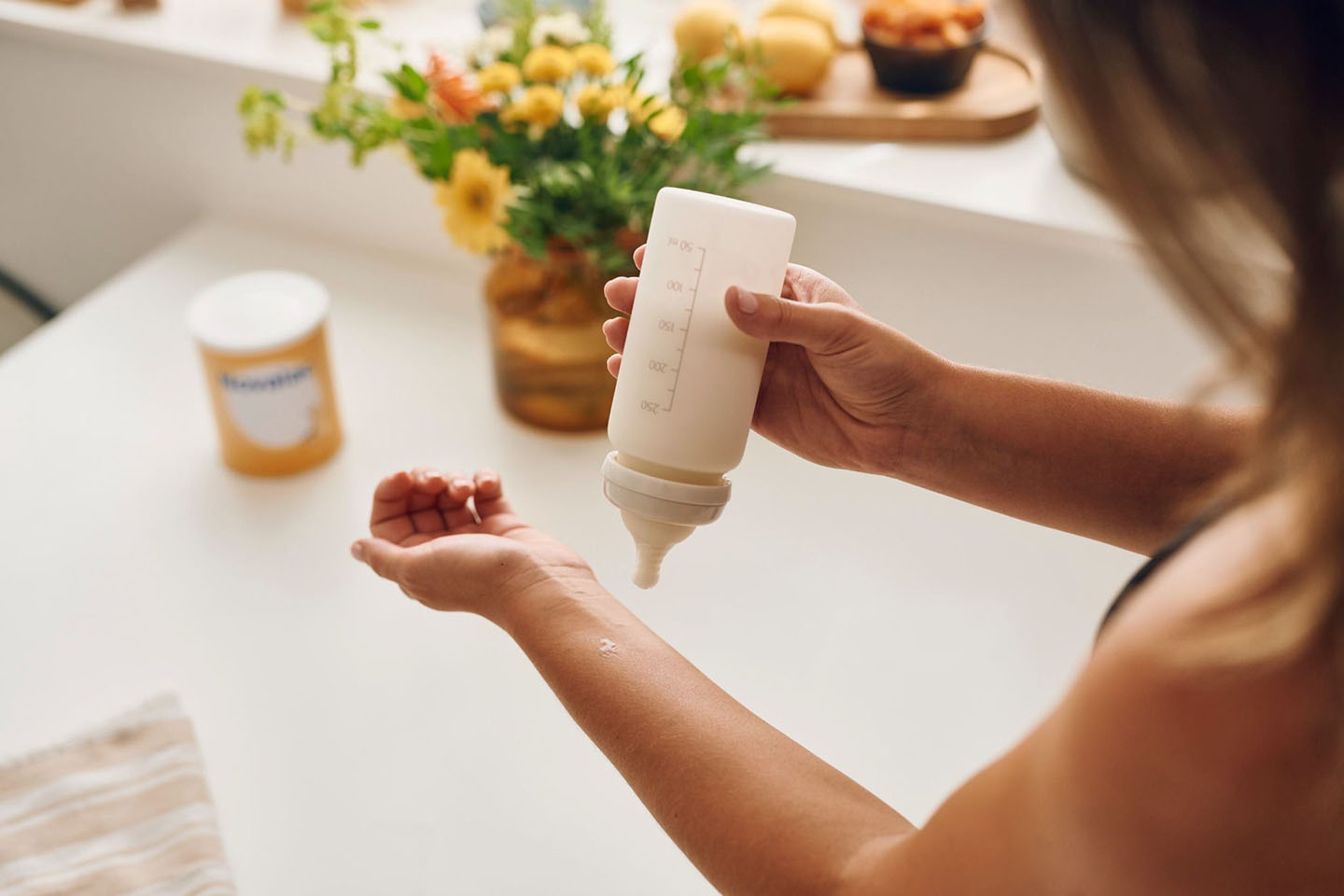 Мама приготвя бутилка мляко в кухнята - подкрепа за алергия към протеина на кравето мляко.