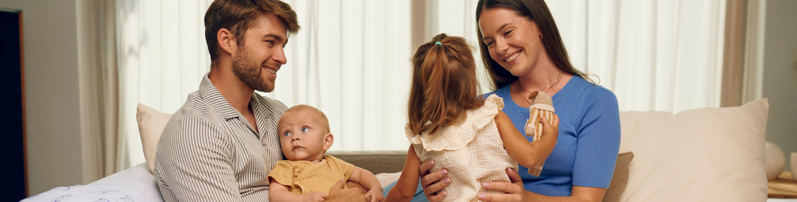 Семейство, седнало на дивана, родители, бебе и едногодишна дъщеря