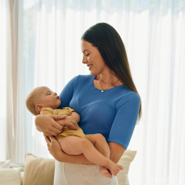 Майка, държаща новородено бебе в светла стая