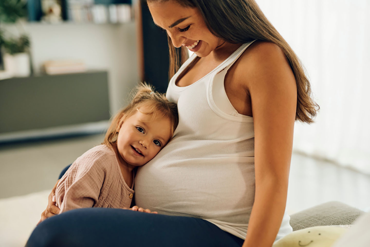 Момиче прегръща корема на бременната си майка